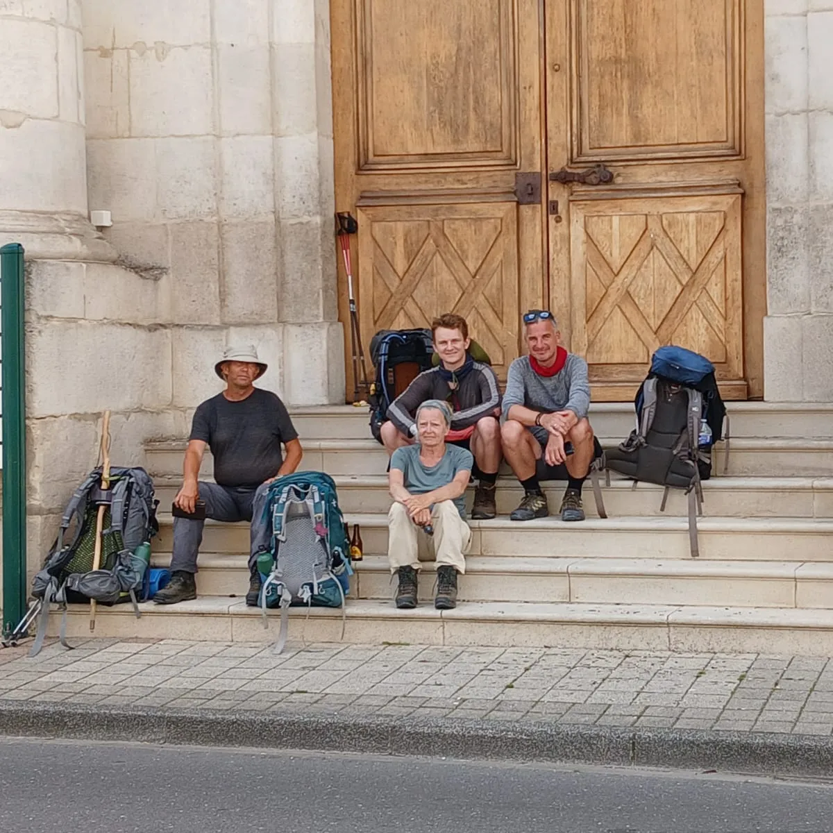 Pilgrimme holder pause ved kirke under pilgrimsvandring på Caminoen i Frankrig